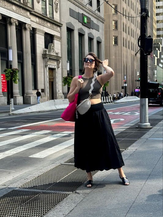 Lisa wearing flowy black skirt, Womads crossbody bag and black peep toe flats standing in the streets of New York. 