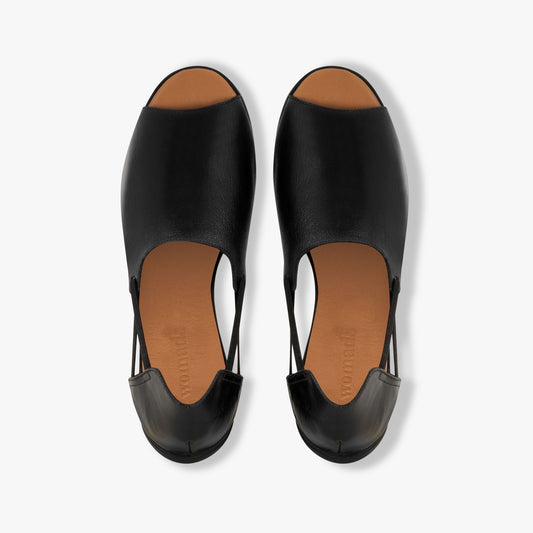 Pair of black open-toe shoes with brown soles on a white background