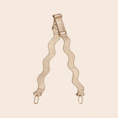gold bag strap with gold hardware on a beige background