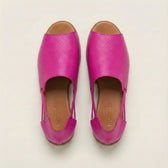 Pair of bright pink shoes with brown soles on a light beige background