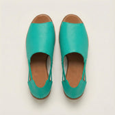 Pair of turquoise sandals with brown soles on a light beige background
