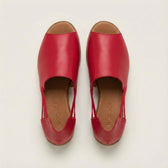 Pair of red leather shoes on a light beige background