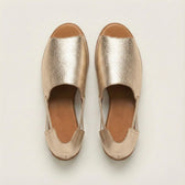 Pair of gold metallic slip-on shoes on a light gray background