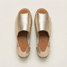 Pair of gold metallic slip-on shoes on a light gray background