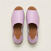 Pair of lavender shoes with brown soles on a light beige background