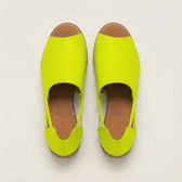 Pair of bright yellow shoes with brown soles on a light gray background