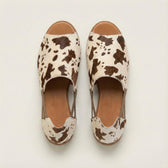 Pair of cow print sandals on a light background