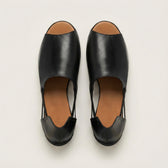 Pair of black open-toe shoes with brown soles on a light gray background