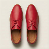 Pair of red leather shoes on a light beige background