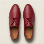 Pair of red leather shoes on a light beige background