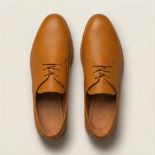 Pair of tan leather shoes on a light beige background