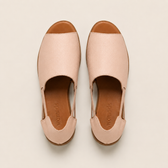 Pair of pink sandals with brown soles on a beige background