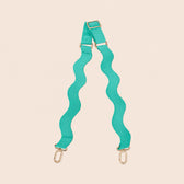 Turquoise bag strap with gold hardware on a beige background