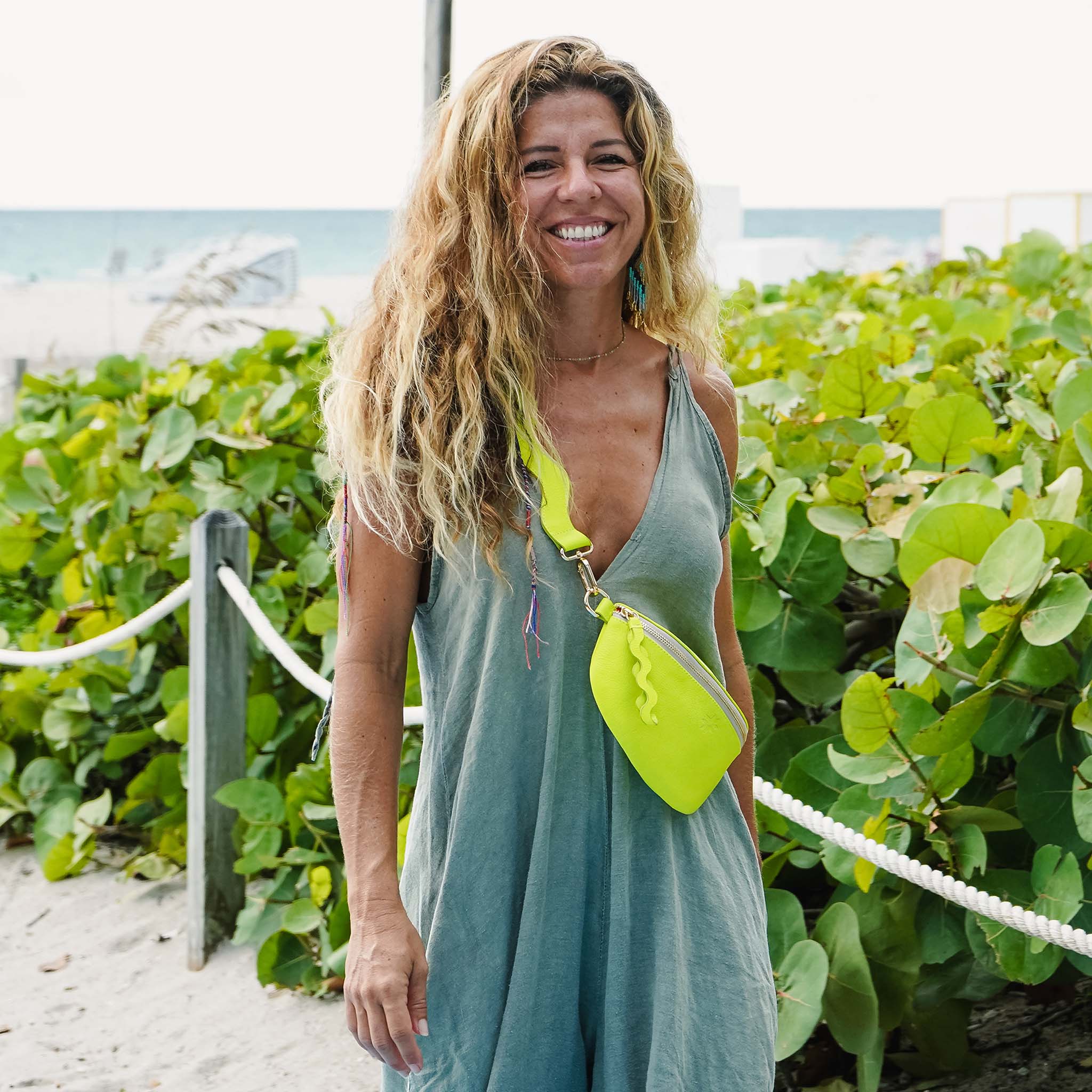 Woman walking on beach with neon green bag