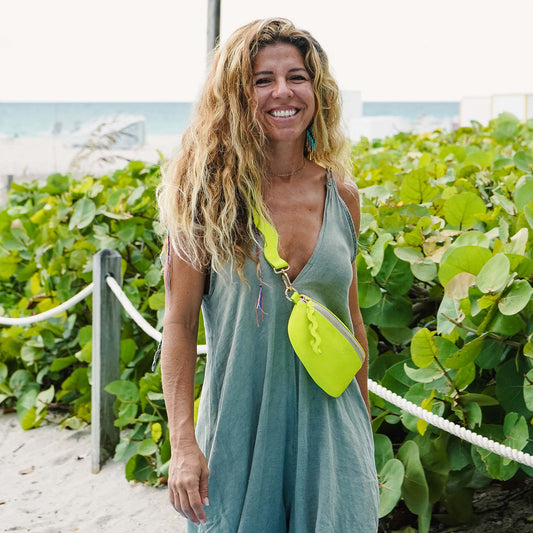 Woman walking on beach with neon green bag