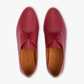 Burgundy leather shoes with brown soles on a white background