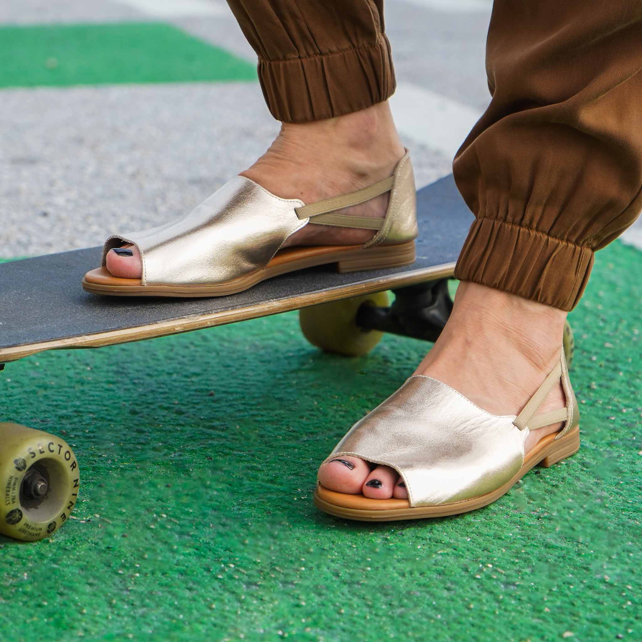 Close up of gold sandals with skateboard