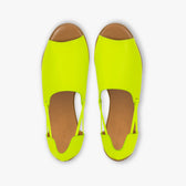 Pair of neon yellow shoes with brown soles on a white background