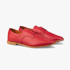 Red leather shoes with brown soles on a white background