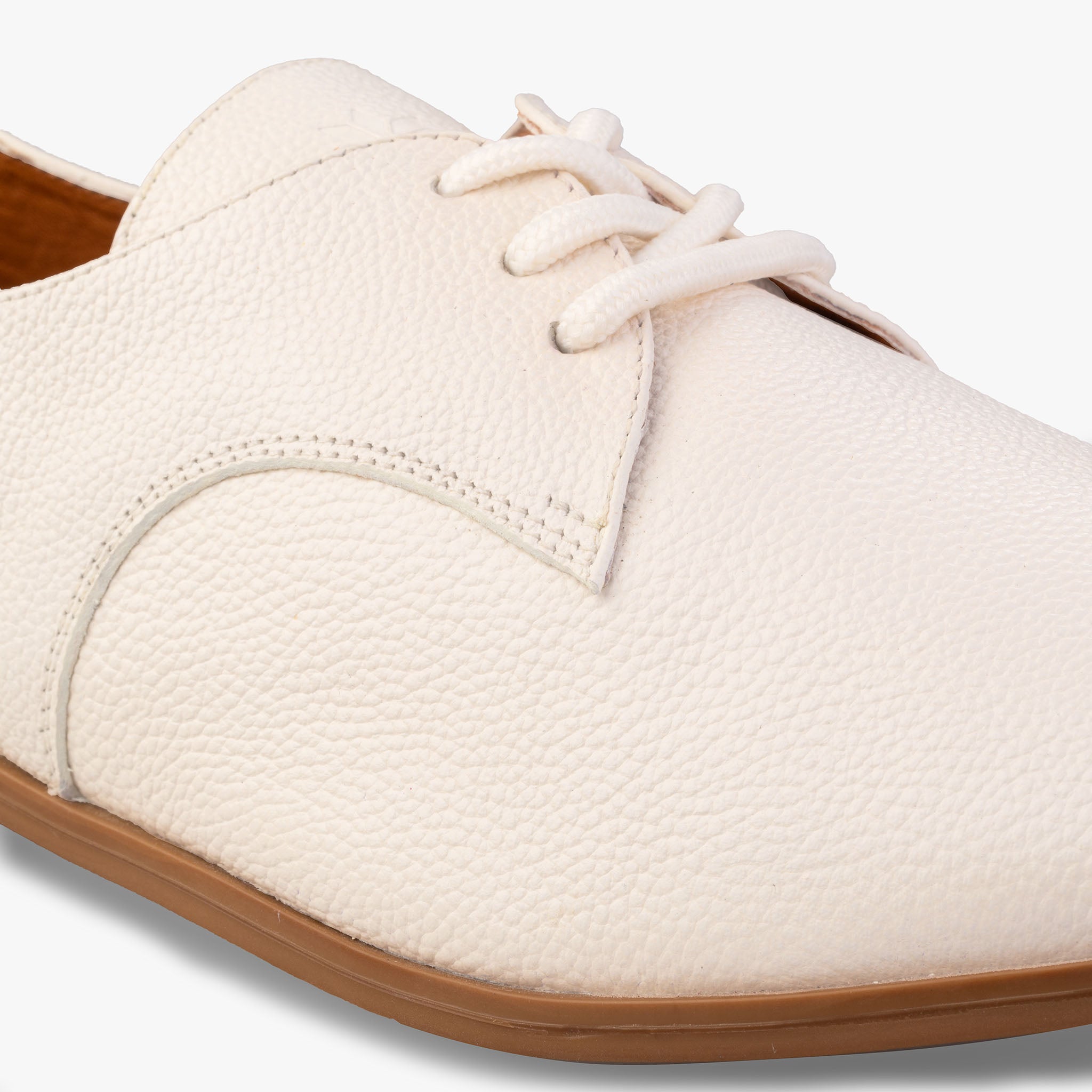 Close-up of a white shoe with brown sole on a white background