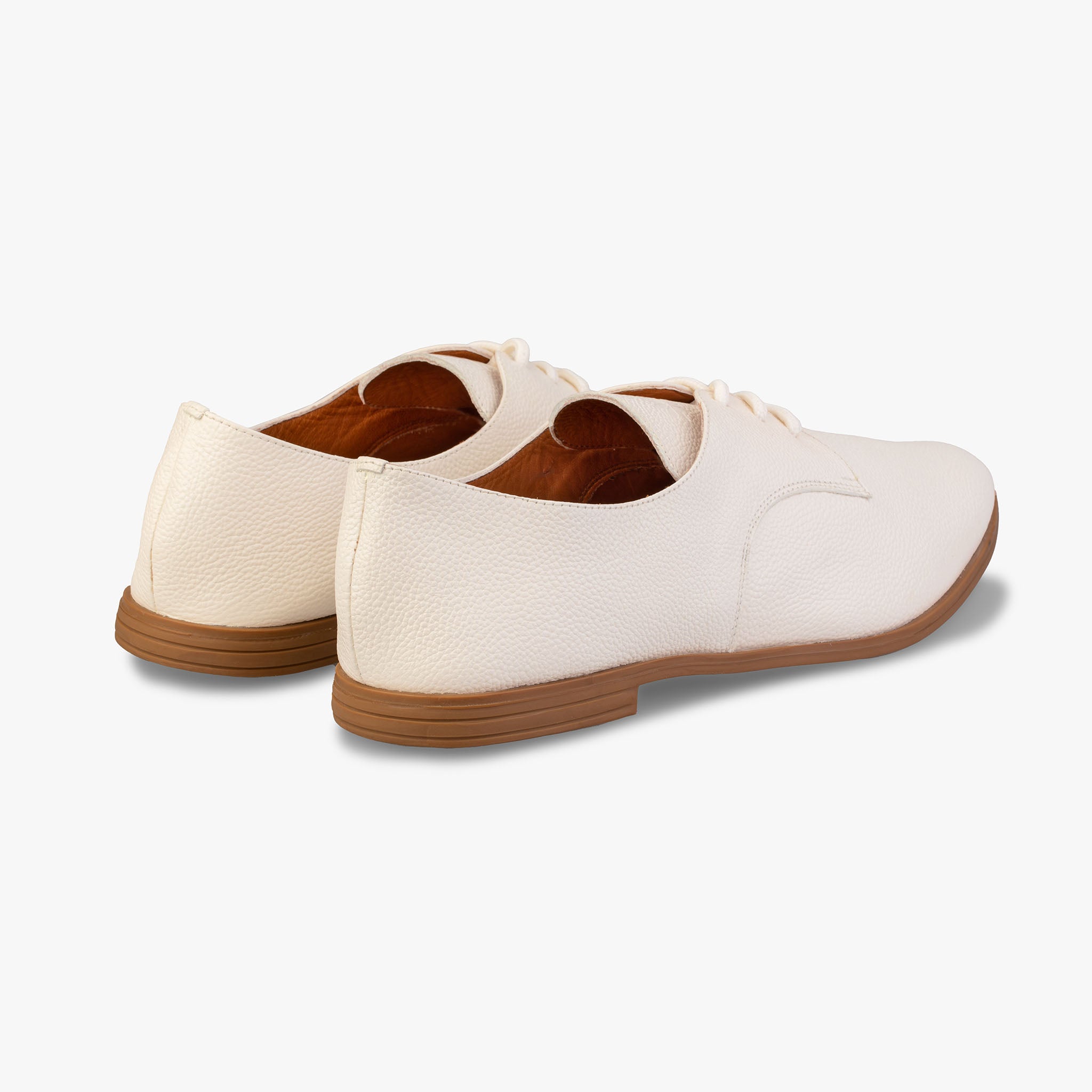 Pair of white shoes with brown soles on a light gray background