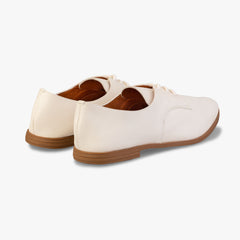 Pair of white shoes with brown soles on a light gray background