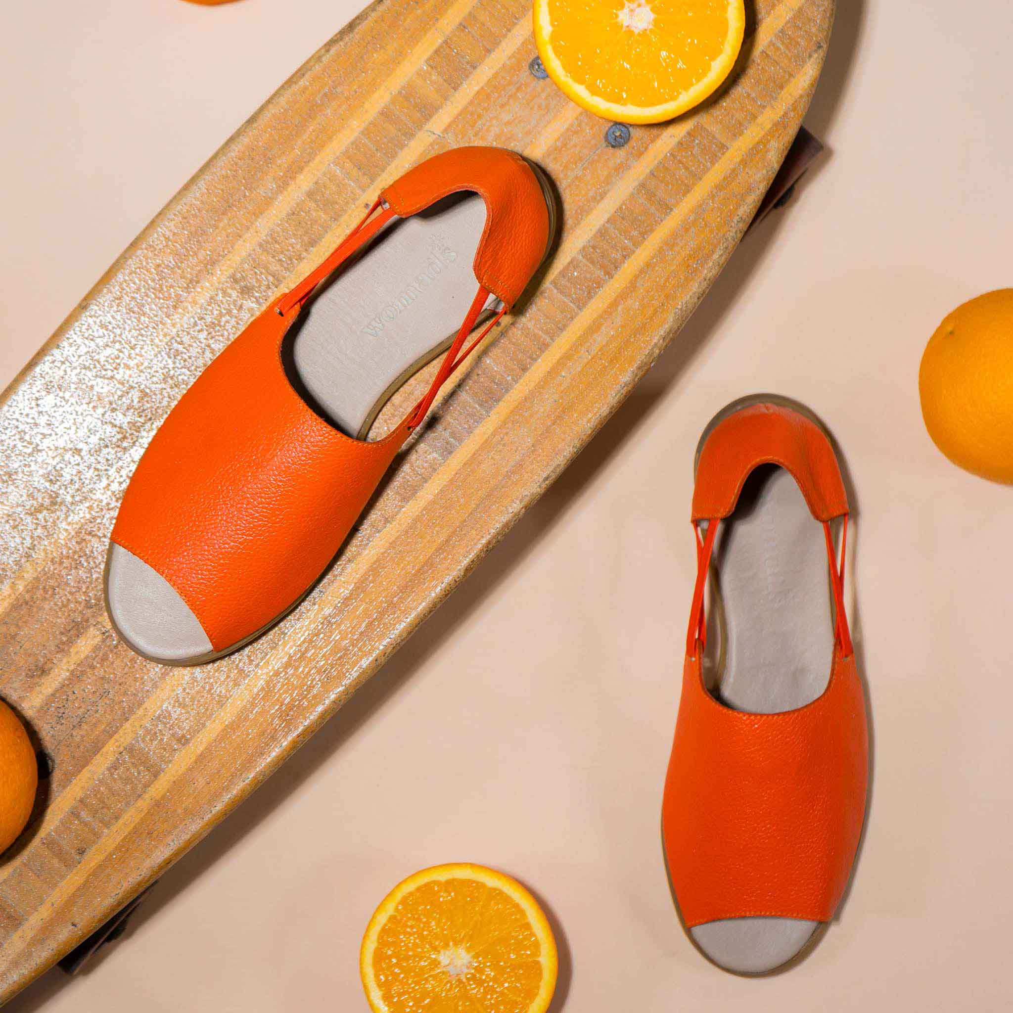 Womads orange sandals on skateboard