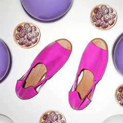 Pink shoes with rubber soles on a white surface with purple balloons and pies.