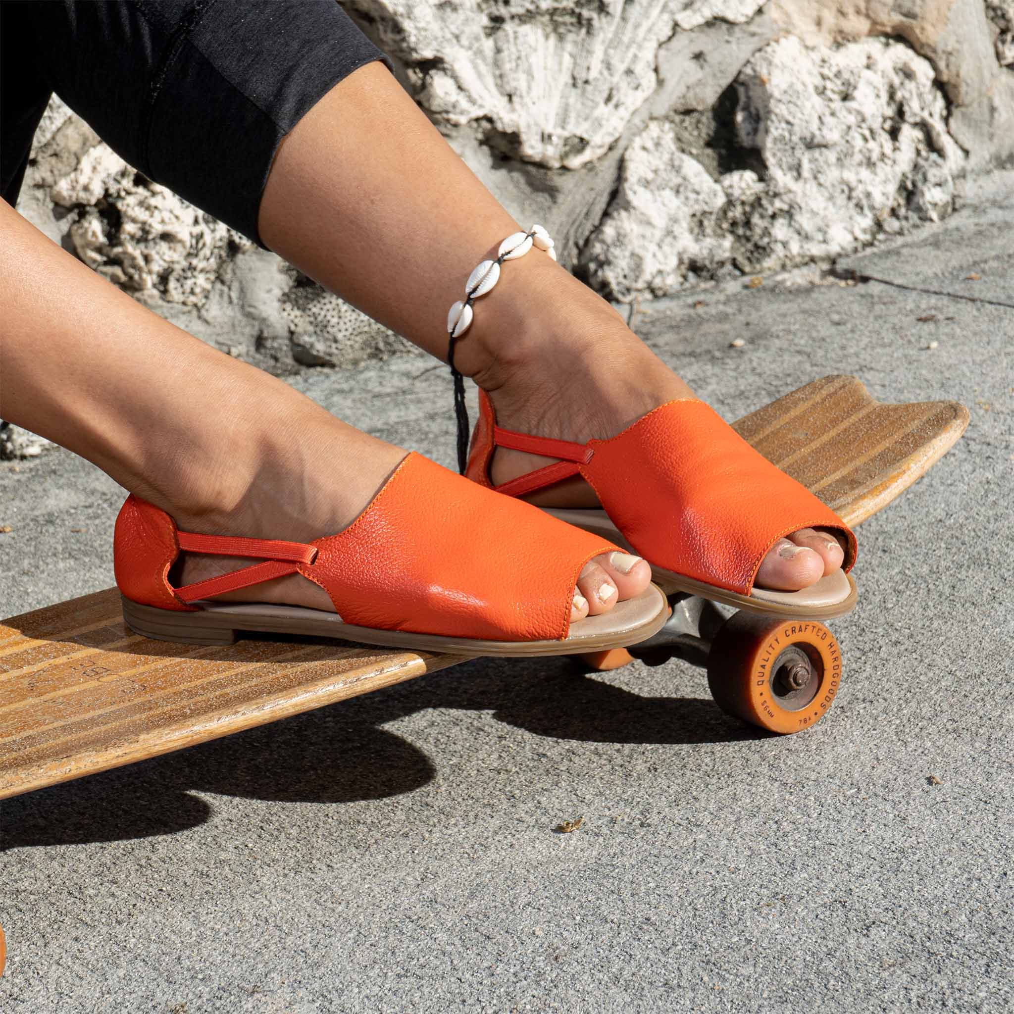 Womads orange sandals worn on skateboard